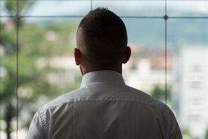 Young Businessman Looking Out Office Window Pondering Future